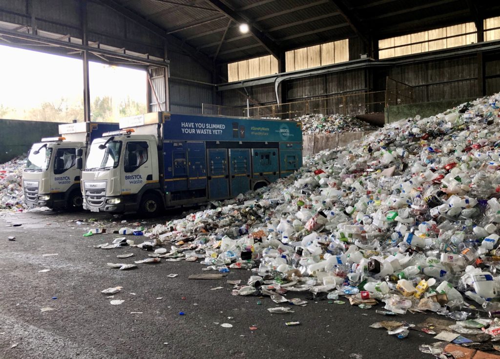 Two Bristol Waste trucks inside transfer station next to recycling