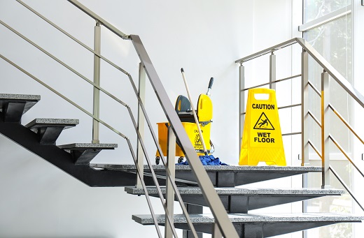 Safety sign with phrase "Caution wet floor" and mop bucket on stairs depicting a cleaning service