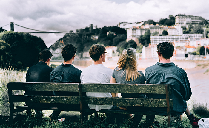 Bristol university students sitting on a bench looking at the city of Bristol