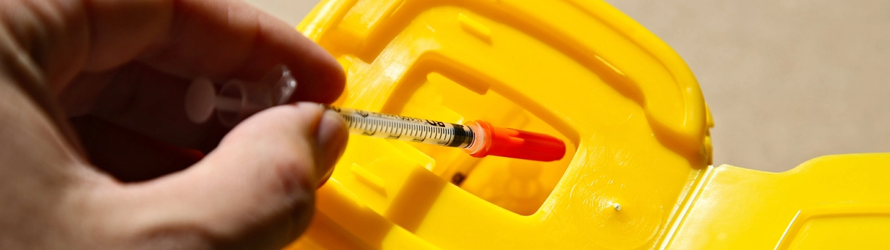 A needle going into a sharps box