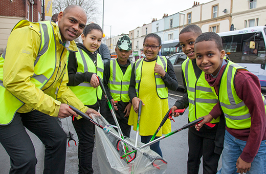 Mayor of Bristol Marvin Rees and a group of school children holding litter pickers.