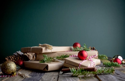 Gifts wrapped in recyclable brown paper with baubles and sprigs of fir tree