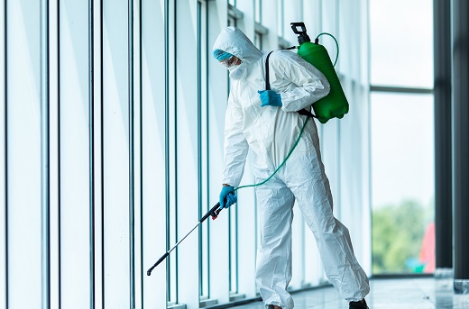 Man in full body suit deep cleaning an office building