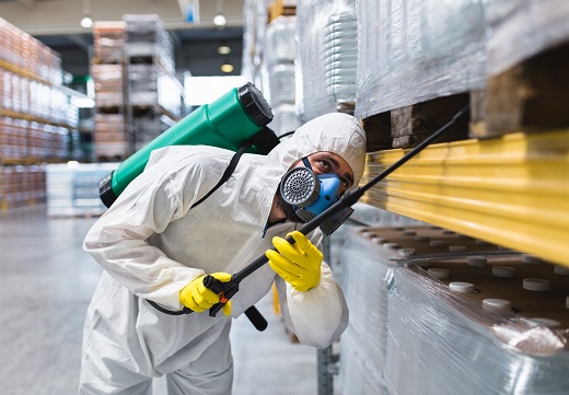 Man with a chemical protection suit doing a deep clean of a warehouse