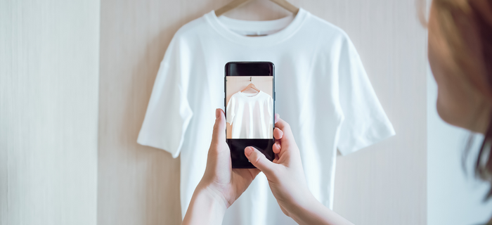 A photo of a white t-shirt being taken on a mobile phone 