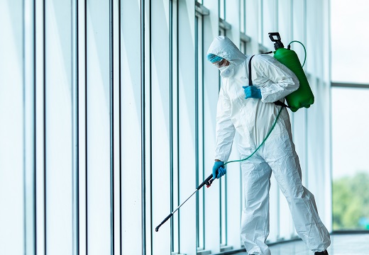 Man with a chemical protection suit cleaning an office building with spray chemicals