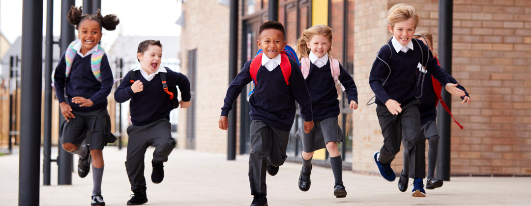 A group of smiling primary school children running towards the camera