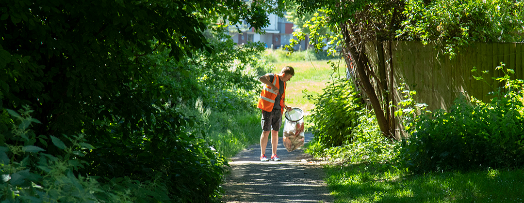 A person litter picking on a shady path during the Great Bristol Spring Clean 2021