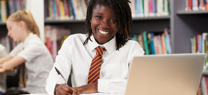 A smiling secondary school student sat at her desk