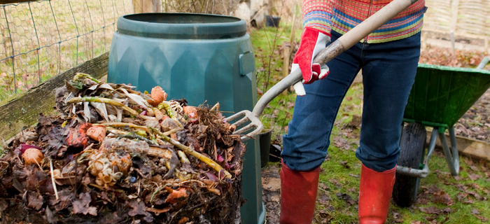 A person turning a compost pile with a garden fork