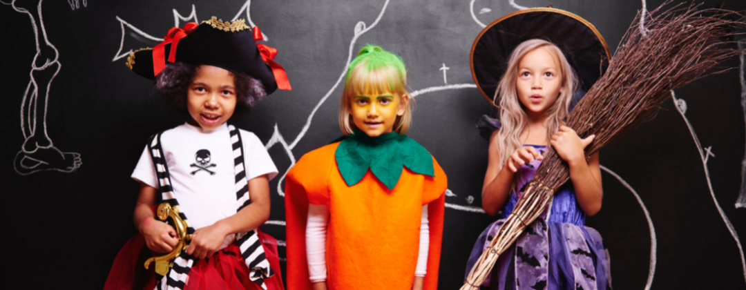 Three children dressed in halloween costumes: a pirate, a pumpkin and a witch.