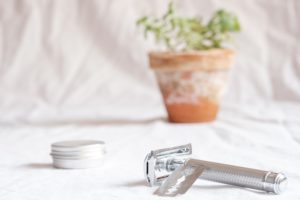 Metal reusable container, razor and a plant in the background
