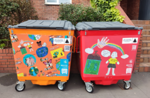 An ornage and red bin decorated with children's art work