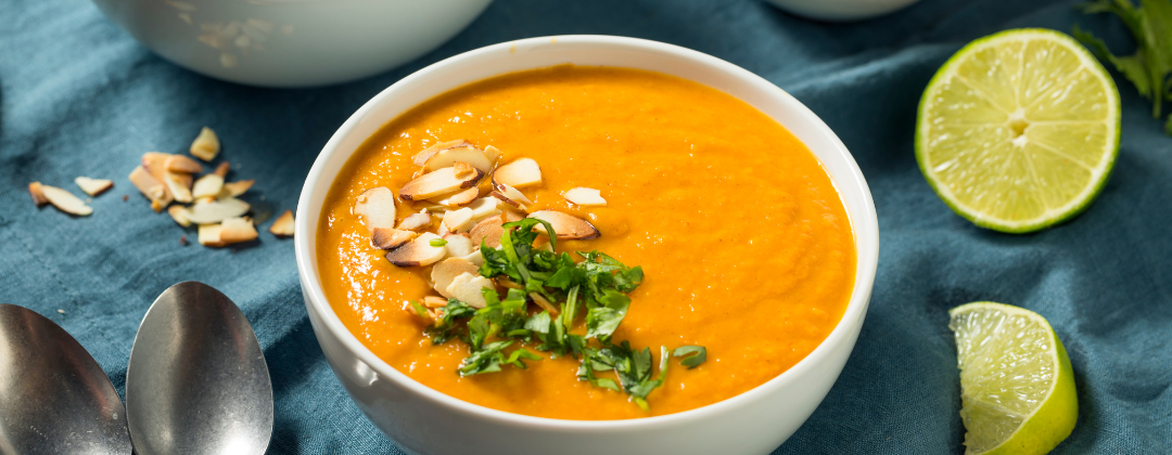 A bowl of pumpkin soup on a table set with a blue table cloth