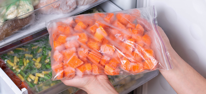 A bag of cubed pumpkin being placed into a freezer 