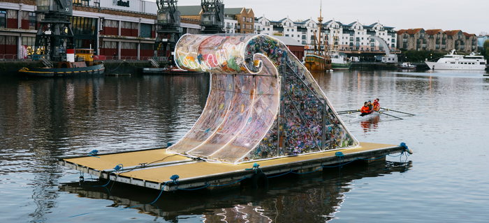 a huge sculpture made of litter in the shape of a wave floating in Bristol harbour
