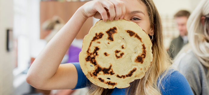 A woman holding a pancake in front of her face.