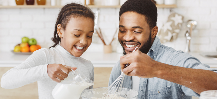 A father and daughter mixing pancake batter together.