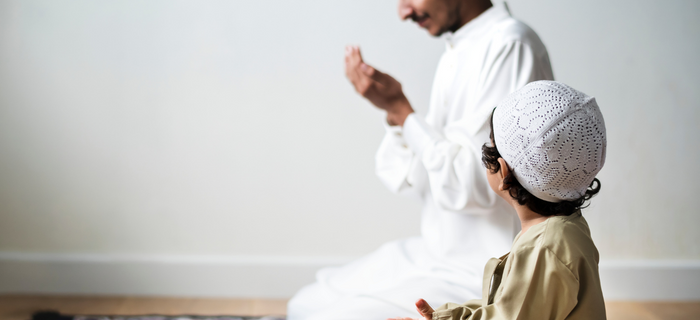A man and a small boy kneeling to pray during Ramadan
