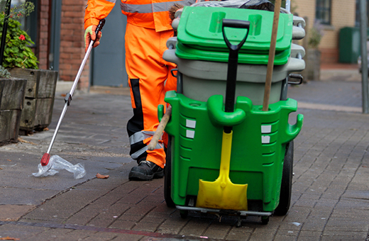 A street cleanser picking up a plastic bottle with litter pickers