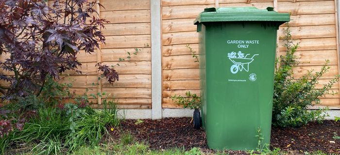 A garden waste bin in a garden