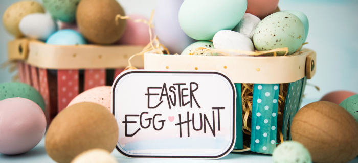 A basket full of painted eggs and wooden eggs with a hand-written sign saying 'Easter egg hunt'.