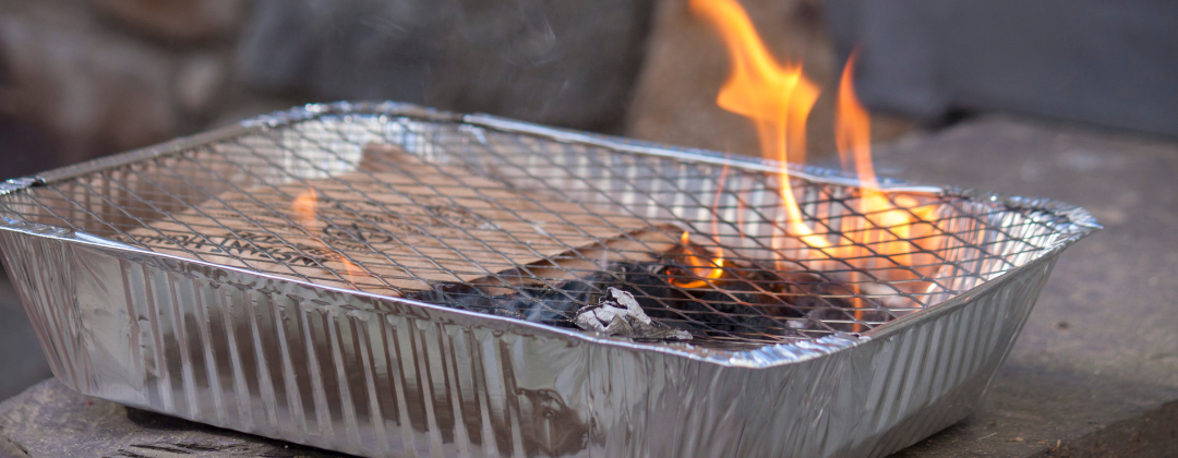 A flame leaps upwards on a newly lit disposable barbecue