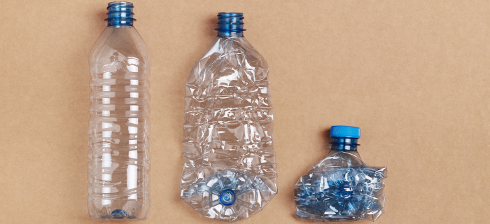 Three plastic bottles on a plain background showing how squashing a bottle can make it smaller. The first bottle isn't squashed, the second bottle is flattened, and the third bottle is compressed down into a fist-sized ball.