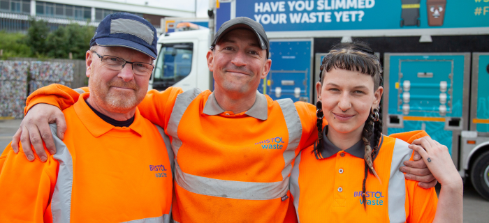 Three Bristol Waste crew members with their arms around one another's shoulders smile at the camera