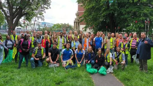 A big group of Big Tidy volunteers from a business, holding litter pickers.