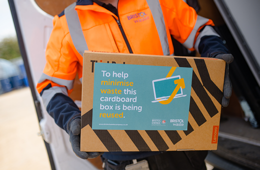 A Bristol Waste employee holding a IT reuse box with a laptop inside