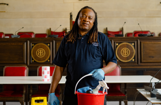 A cleaner standing inside Bristol's city hall holding a bucket full of cleaning products conducting a deep clean.