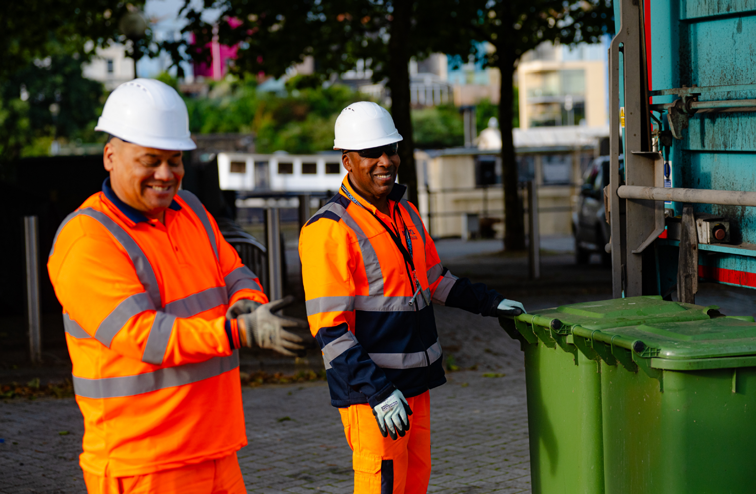 Two smiling Bristol Waste colleagues collect a large bin