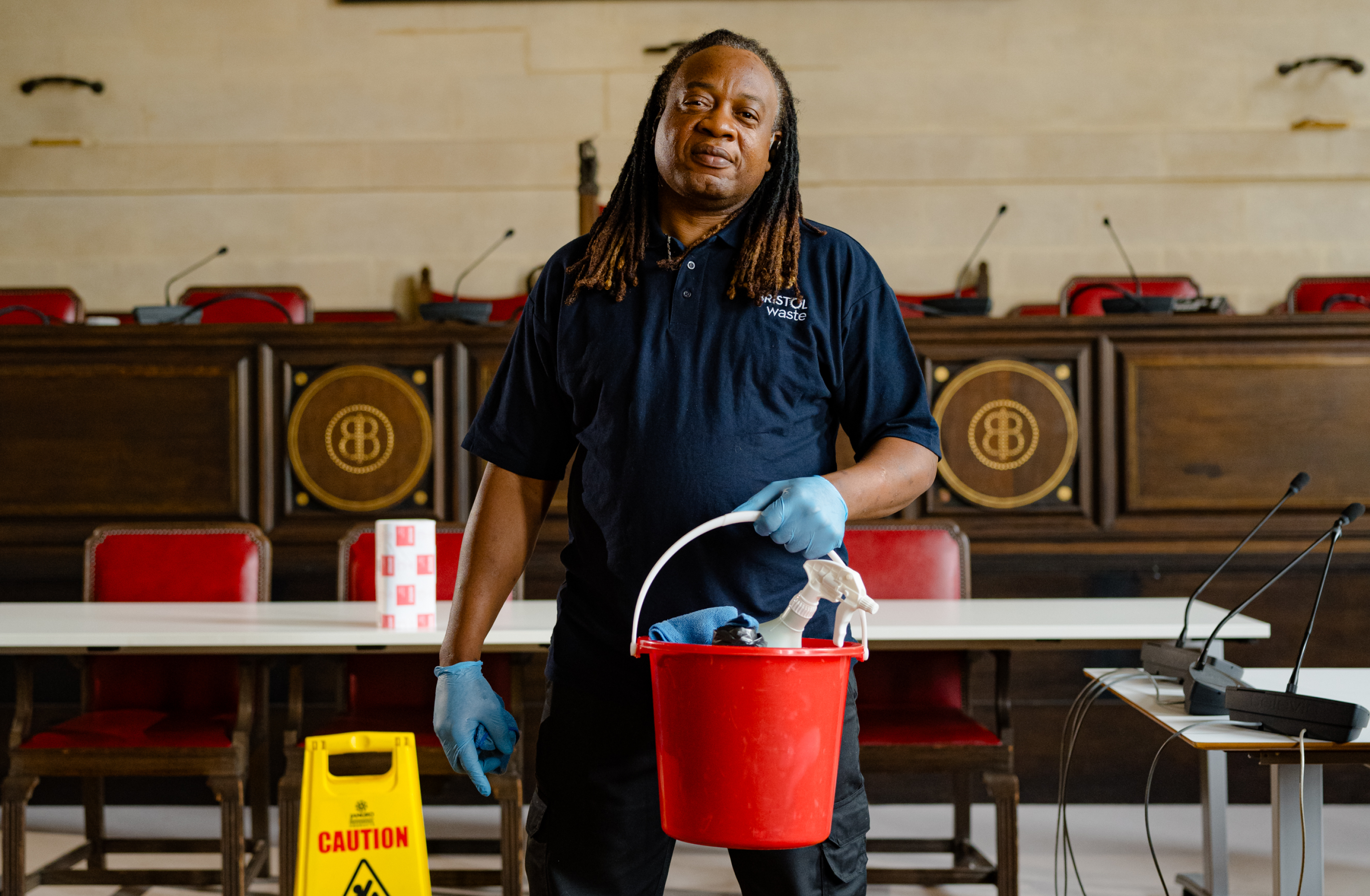 A cleaner with gloves, a bucket and cleaning supplies