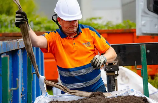 a Bristol Waste crew member loading up compost into a bag using a crane.