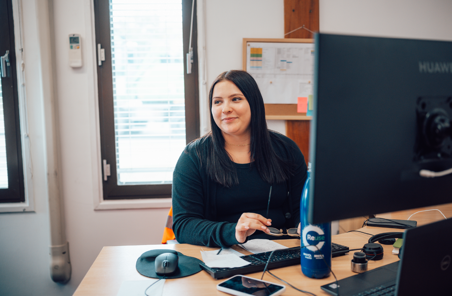 A woman is sitting at a computer in an office