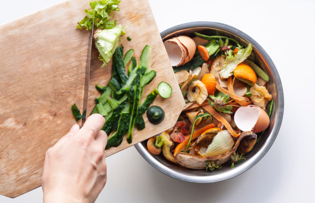 Hand using knife to push food scraps into waste bin