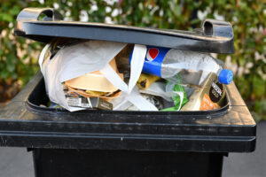 A general waste bin, overflowing with rubbish and recyclable materials