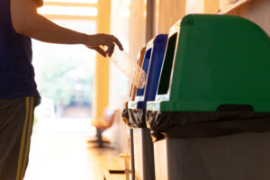 Person placing empty plastic bottle into a bin