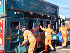 Three Bristol Waste team members load recycling containers into a Bristol Waste truck. It's bin day for this street