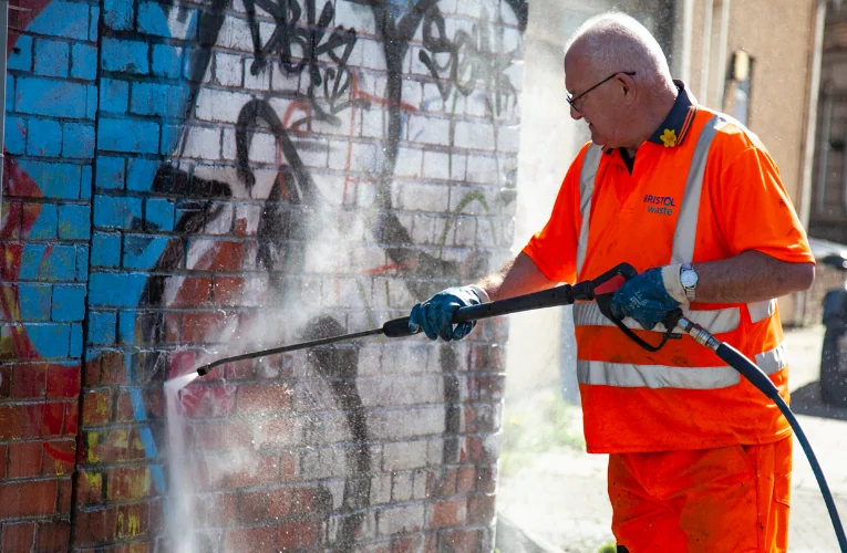 Man spraying graffiti from brick wall