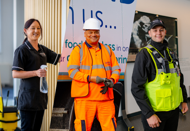 A woman cleaning, a man in high vis and hard hat, a man in security guard clothing