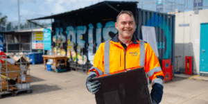 Man in hi-visibility clothing carrying a computer tower