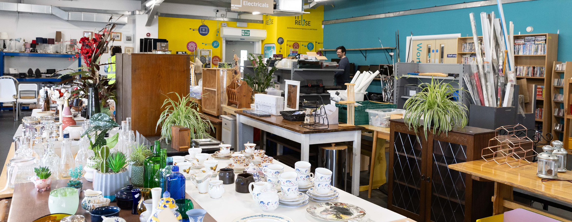 The inside of Bristol Waste's Hartcliffe Way Reuse Shop. There are lots of items for sale including furniture, electricals, potted houseplants and crockery