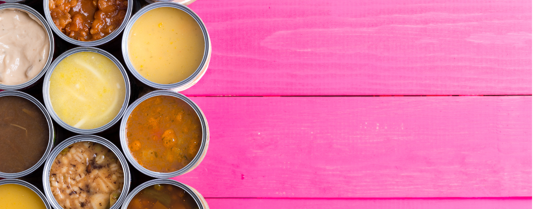 A selection of tins of liquid food on a pink wooden background