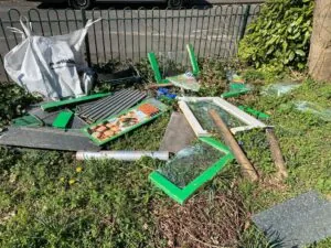 A fly-tip on a grassy area, made up of wood and broken glass