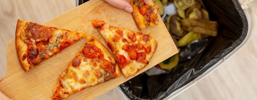 Pizza slices in front of a waste bin