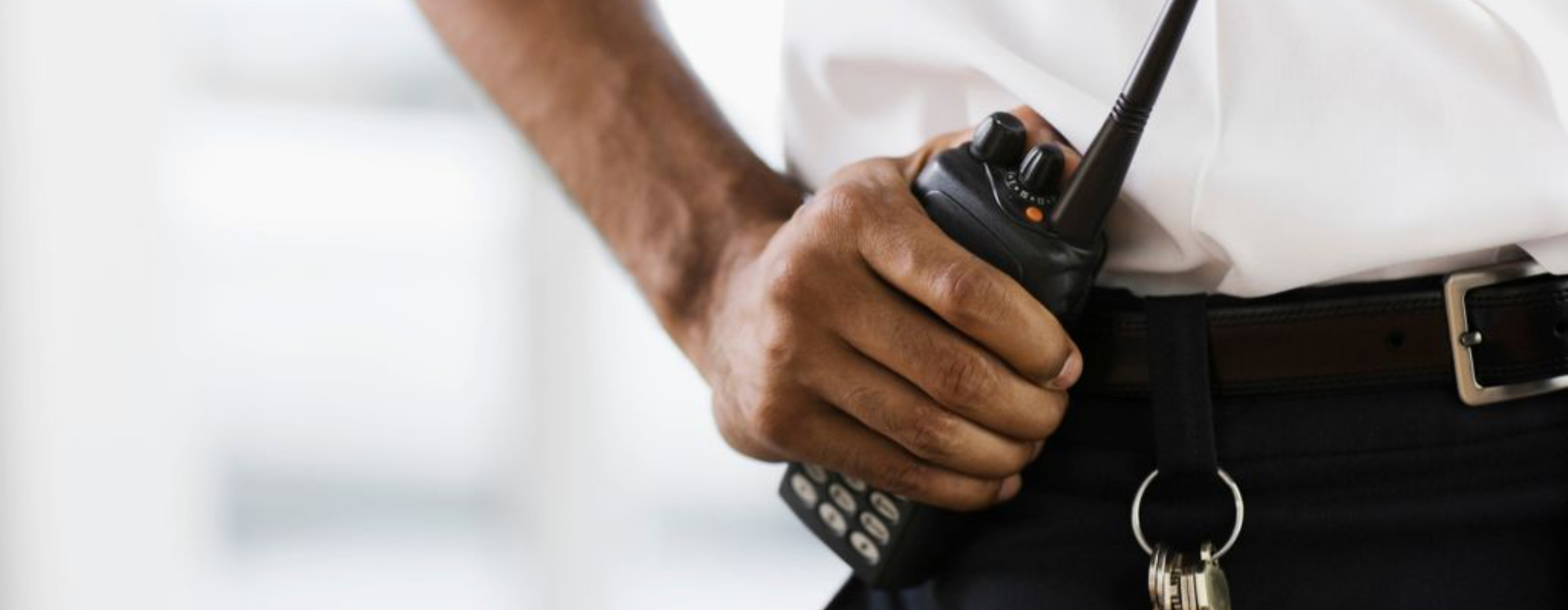 Security guard holding walkie-talkie on their belt.