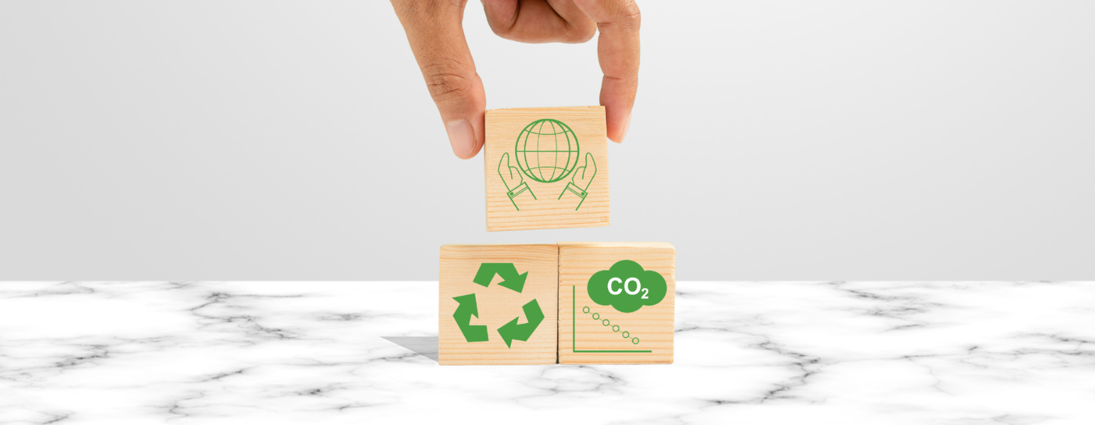 A hand placing a wooden block on top of a stack of 3 wooden blocks with carbon emissions symbols