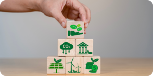 A hand placing a wooden block on top of a stack of wooden blocks with scope 1, scope 2 and scope 3 emissions symbols